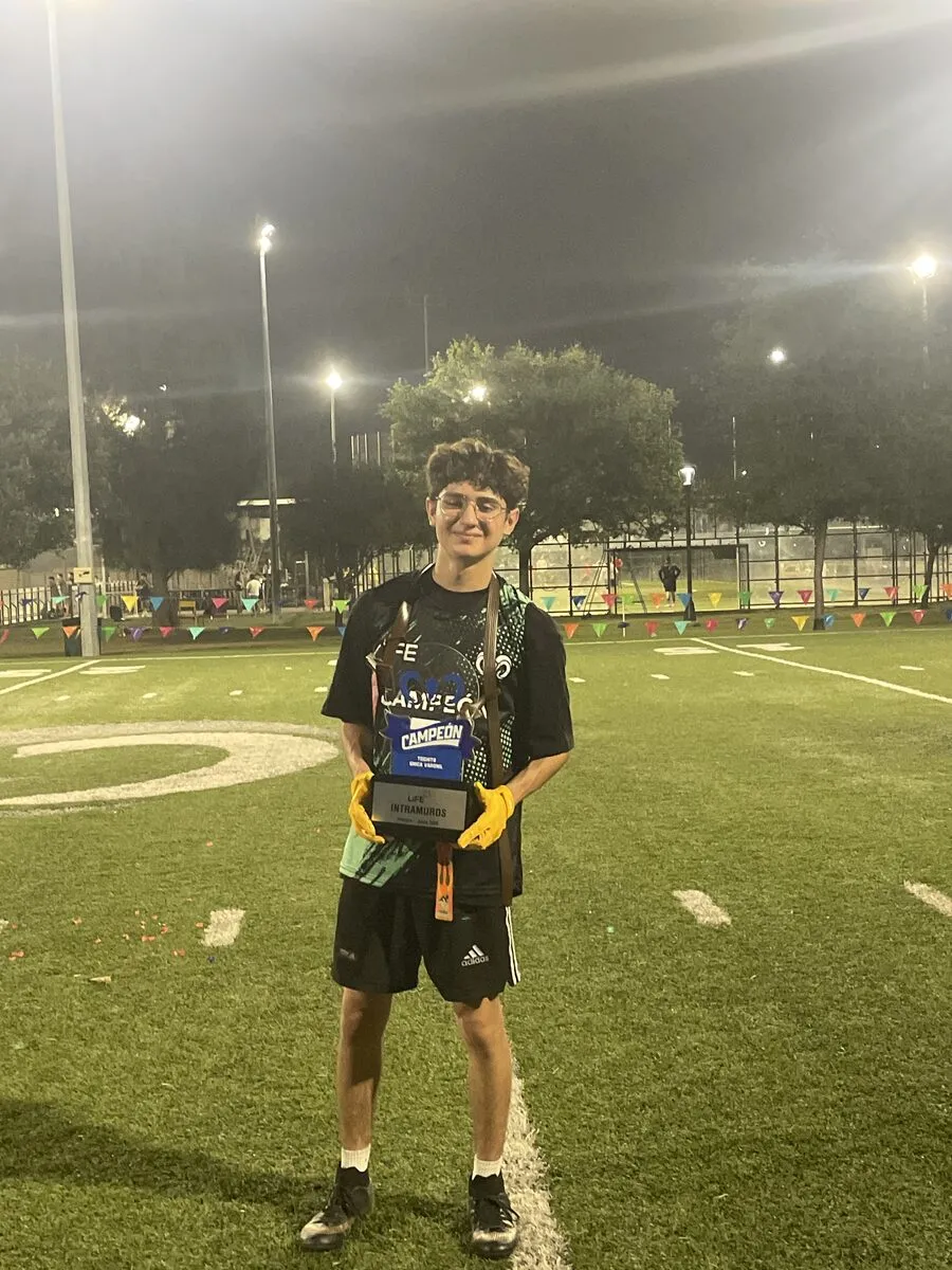 Holding a champion plaque on a soccer field at night