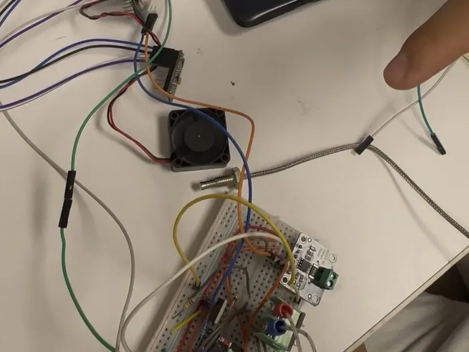 SentinelBox electronics prototype on a workbench, with ESP32 boards, sensor wiring, and a test fan